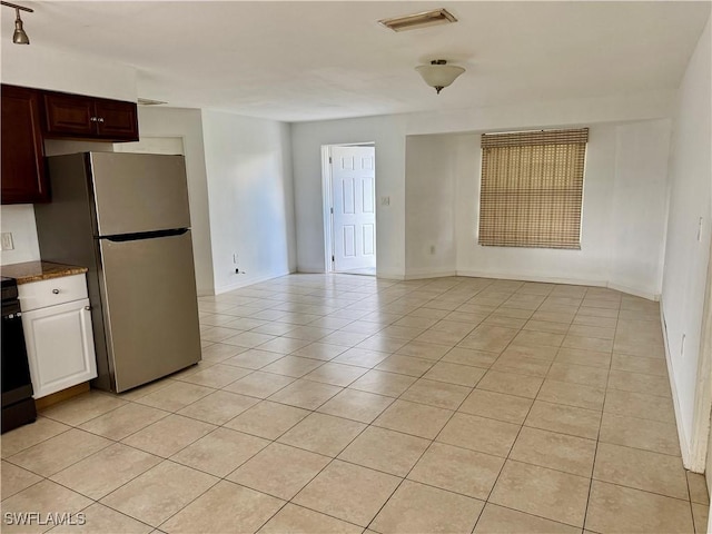 kitchen with light tile patterned floors, stone counters, and stainless steel fridge