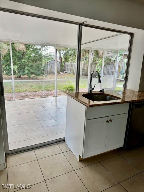 doorway with sink, light tile patterned floors, and plenty of natural light