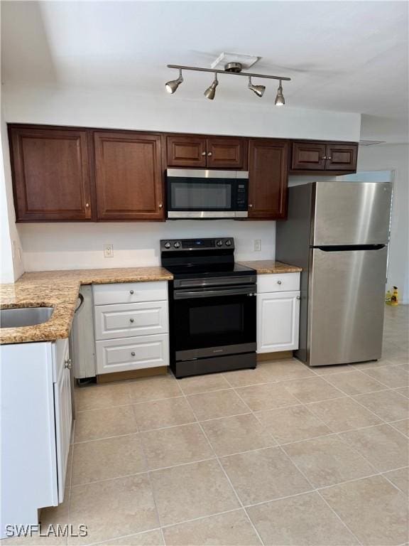 kitchen featuring stainless steel appliances, light stone counters, sink, white cabinetry, and light tile patterned flooring