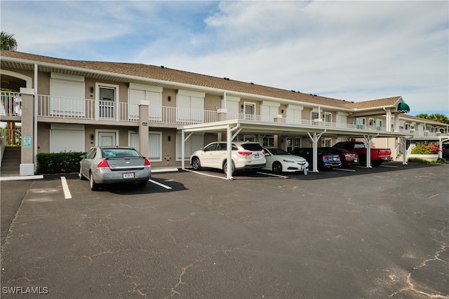 view of building exterior featuring covered and uncovered parking