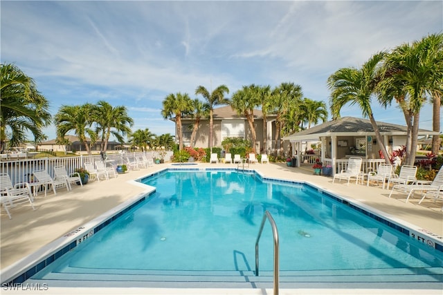 community pool with a patio and fence