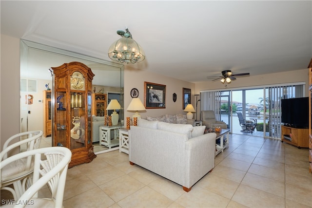 tiled living room with ceiling fan with notable chandelier