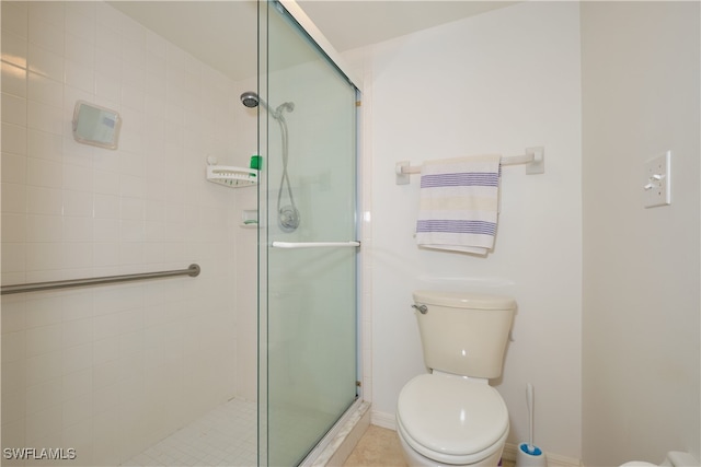 bathroom featuring a shower with door and toilet