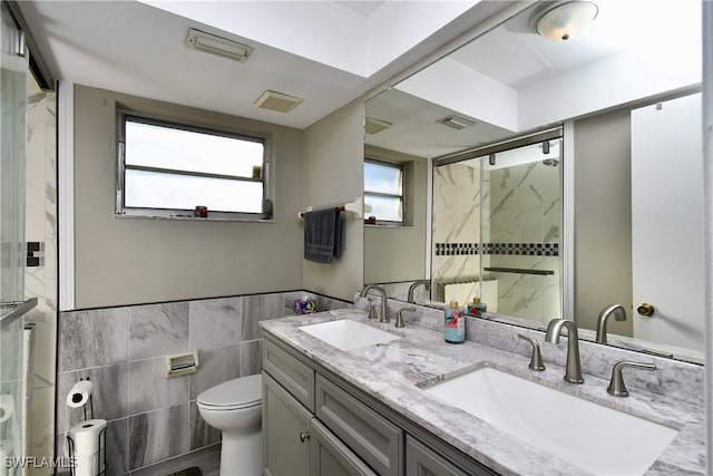 bathroom with vanity, toilet, an enclosed shower, and tile walls