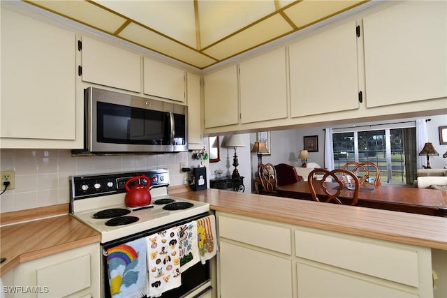 kitchen featuring cream cabinets, tasteful backsplash, and white range with electric stovetop