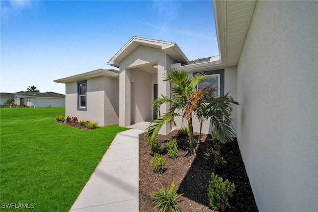 view of exterior entry featuring a lawn