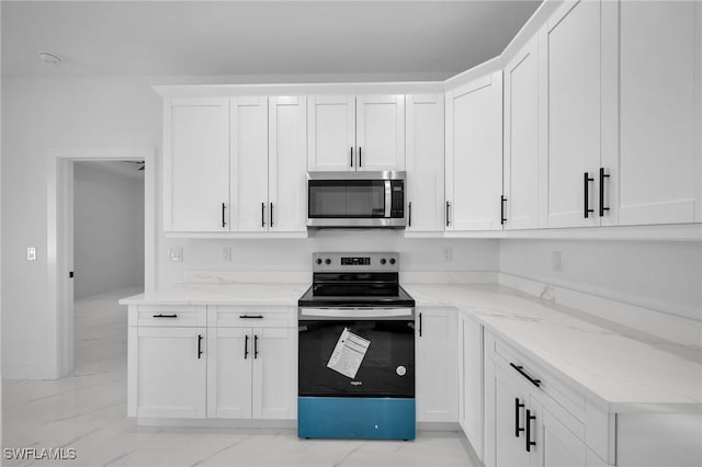 kitchen featuring light stone countertops, white cabinets, and stainless steel appliances