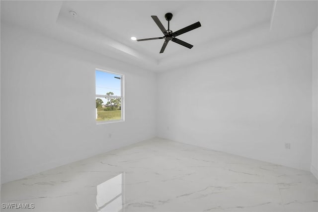 unfurnished room featuring a raised ceiling and ceiling fan