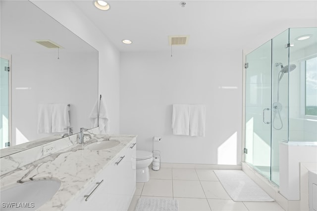 bathroom with tile patterned floors, toilet, a shower with door, and a wealth of natural light