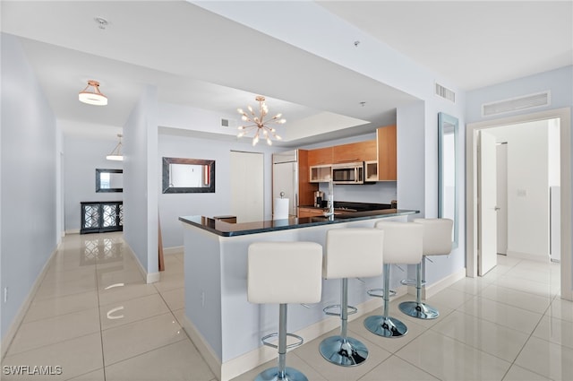 kitchen featuring built in fridge, kitchen peninsula, a chandelier, a breakfast bar, and light tile patterned floors