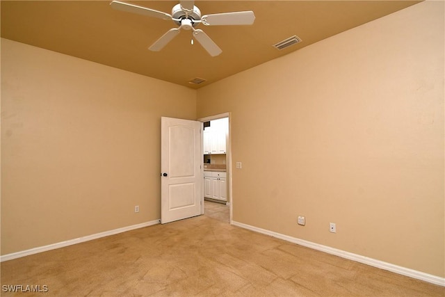 spare room featuring ceiling fan and light carpet