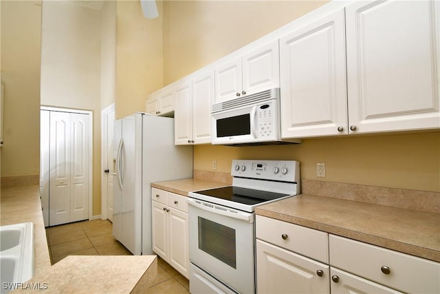 kitchen featuring light tile patterned floors, white appliances, and white cabinetry