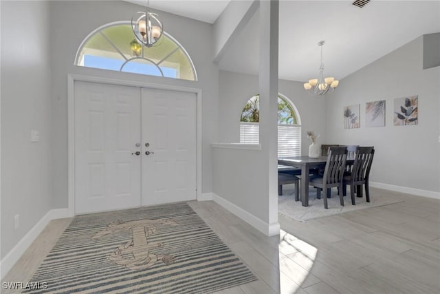 foyer entrance with high vaulted ceiling, an inviting chandelier, and a healthy amount of sunlight