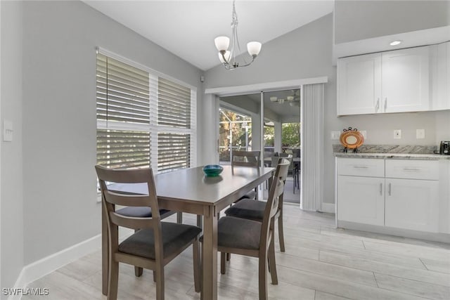 dining area with light wood-type flooring, lofted ceiling, and a notable chandelier