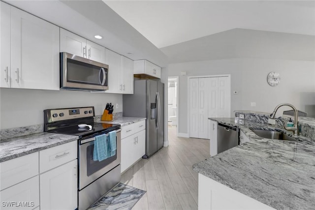 kitchen with light stone countertops, white cabinetry, sink, appliances with stainless steel finishes, and light wood-type flooring