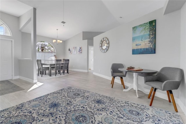 living room featuring lofted ceiling, light hardwood / wood-style floors, plenty of natural light, and a notable chandelier