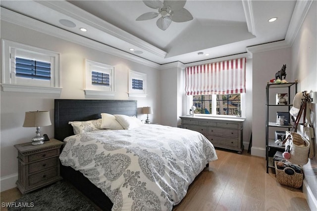 bedroom with recessed lighting, wood finished floors, vaulted ceiling, a raised ceiling, and crown molding