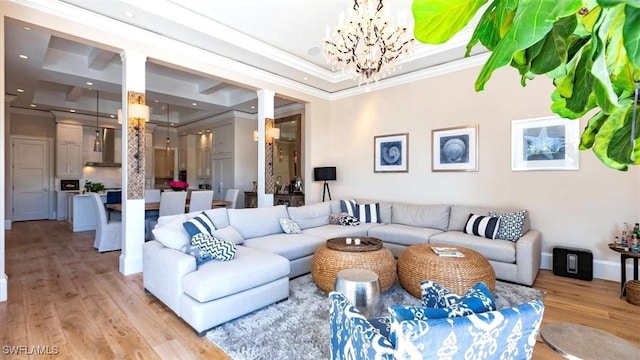 living room with a notable chandelier, light wood finished floors, recessed lighting, a raised ceiling, and ornamental molding