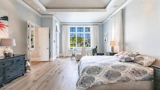 bedroom featuring baseboards, a tray ceiling, wood finished floors, and ornamental molding