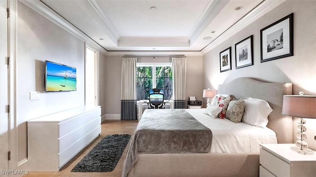 bedroom featuring light wood-style floors, baseboards, ornamental molding, and a raised ceiling