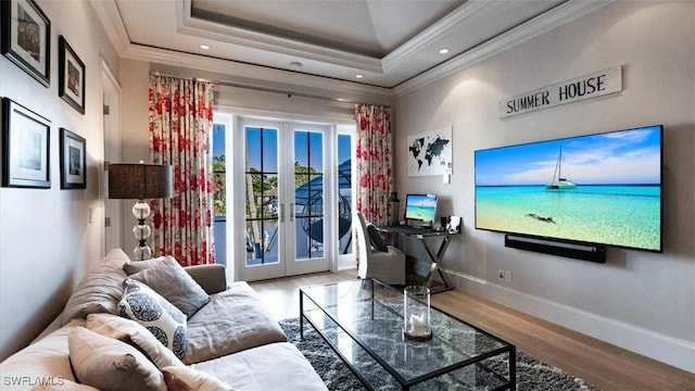 interior space featuring a tray ceiling, french doors, crown molding, wood finished floors, and baseboards