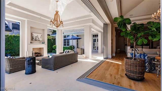 sitting room with wood-type flooring, a fireplace, a raised ceiling, and a notable chandelier