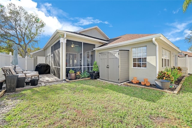 back of house featuring a sunroom, stucco siding, a yard, an outdoor structure, and a fenced backyard