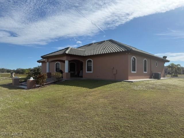 back of house with central air condition unit and a yard