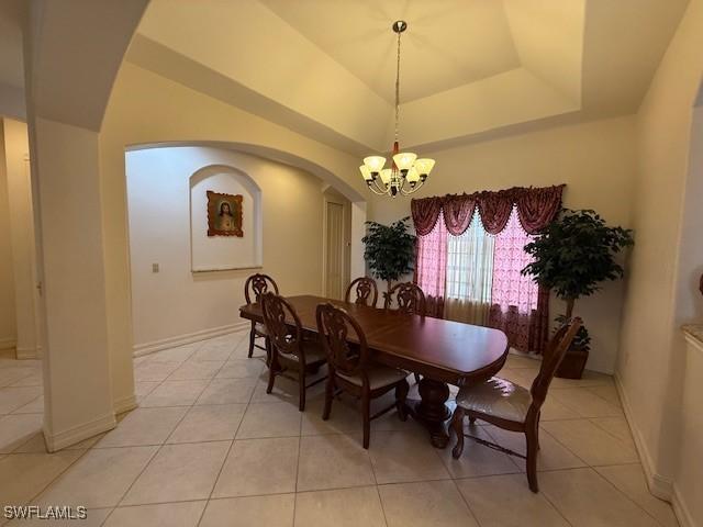 dining room featuring a raised ceiling, light tile patterned floors, and a chandelier