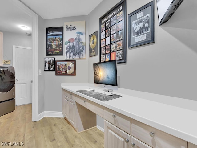 office featuring washer / clothes dryer, built in desk, and light hardwood / wood-style floors