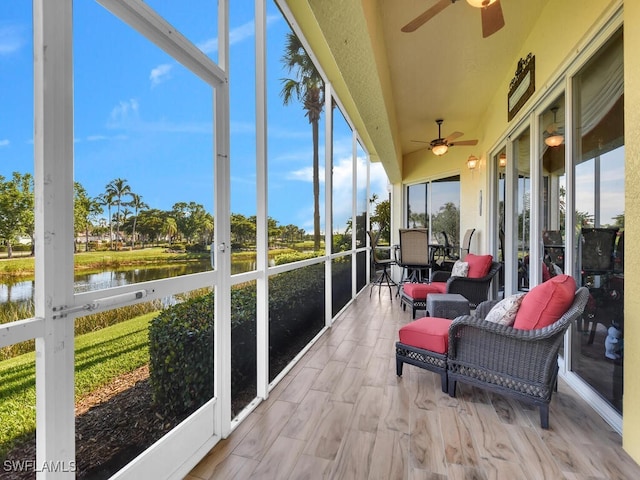 sunroom / solarium featuring ceiling fan and a water view