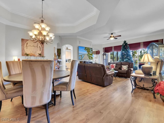 dining space featuring ceiling fan with notable chandelier, crown molding, light hardwood / wood-style flooring, and a tray ceiling