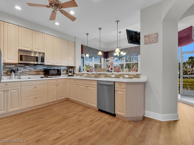 kitchen featuring pendant lighting, backsplash, black appliances, ceiling fan with notable chandelier, and light hardwood / wood-style floors