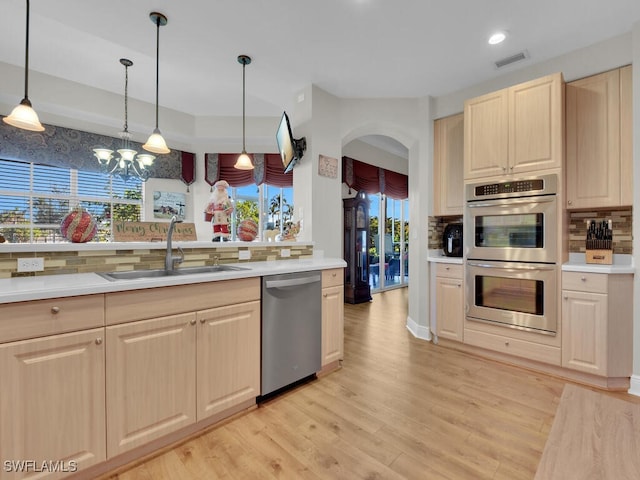 kitchen with arched walkways, visible vents, backsplash, appliances with stainless steel finishes, and a sink