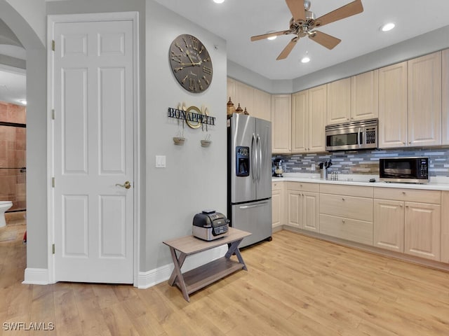 kitchen with decorative backsplash, light wood-type flooring, stainless steel appliances, and ceiling fan