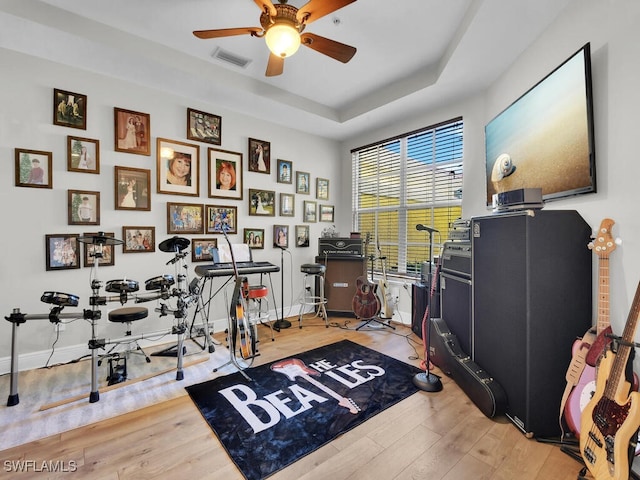 miscellaneous room featuring light wood-type flooring, a raised ceiling, and ceiling fan