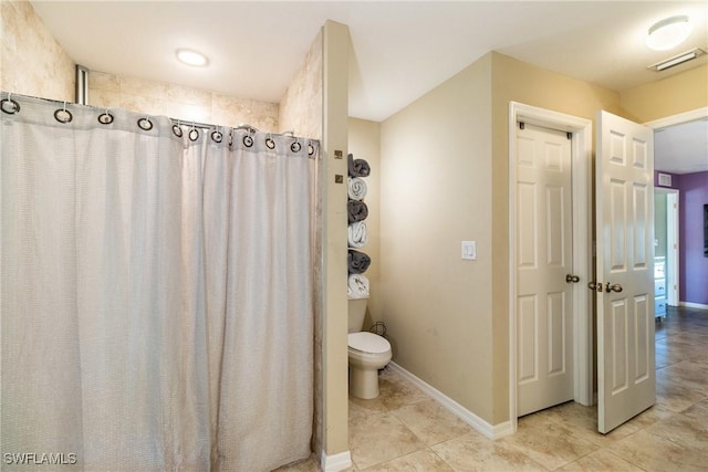 bathroom with tile patterned floors, walk in shower, and toilet