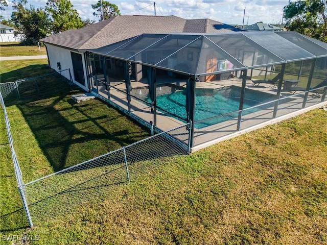 view of swimming pool with glass enclosure, a patio area, and a lawn