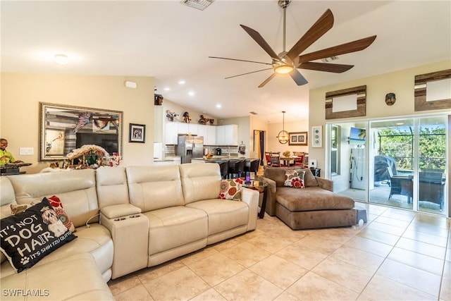 living room featuring ceiling fan, light tile patterned floors, and vaulted ceiling