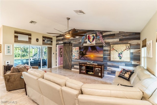 tiled living room featuring a barn door, ceiling fan, and vaulted ceiling