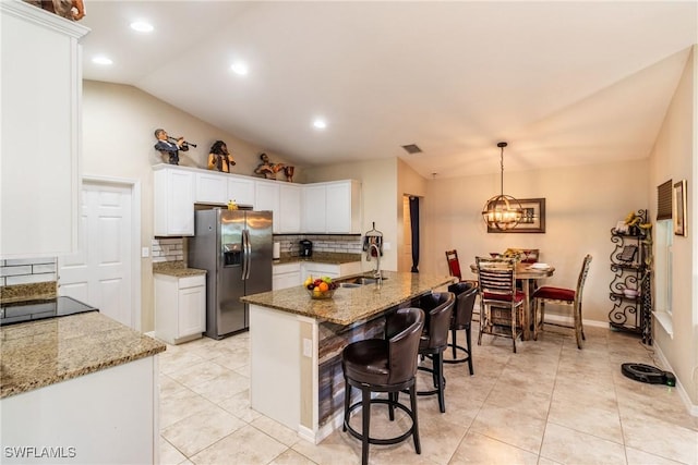 kitchen featuring decorative backsplash, stainless steel refrigerator with ice dispenser, vaulted ceiling, sink, and white cabinetry