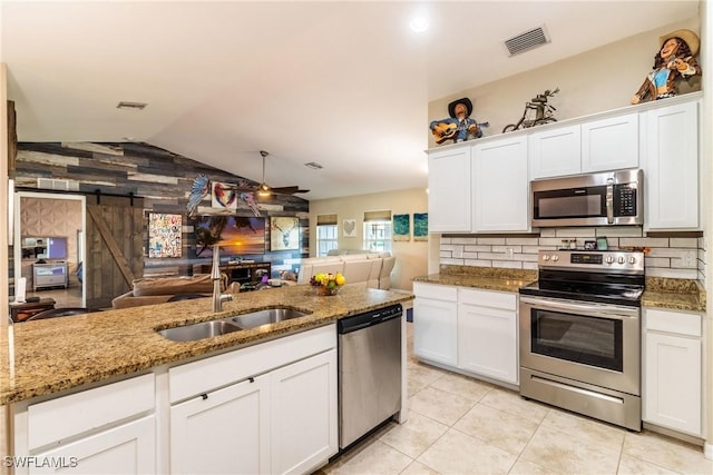 kitchen featuring a barn door, white cabinets, and stainless steel appliances