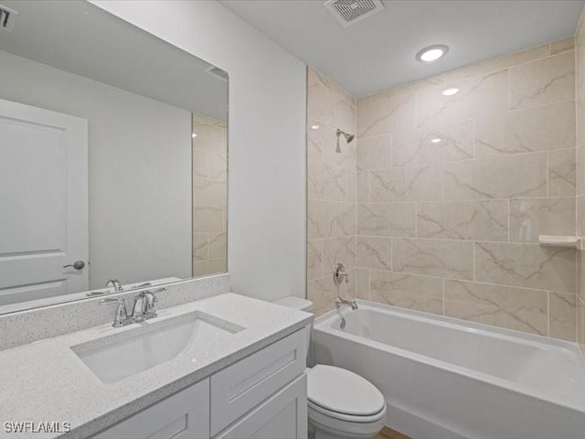 full bathroom featuring vanity, tiled shower / bath combo, and toilet