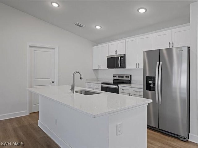 kitchen with white cabinets, appliances with stainless steel finishes, a center island with sink, and sink