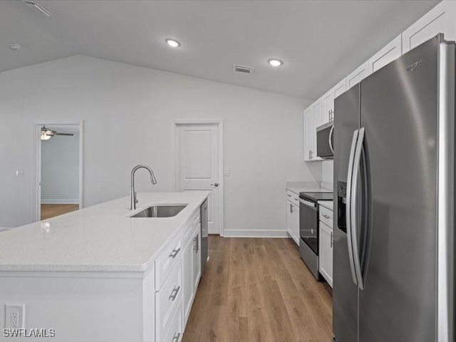 kitchen with a kitchen island with sink, white cabinets, sink, vaulted ceiling, and stainless steel appliances