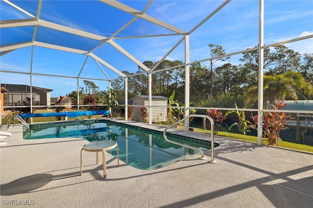 view of swimming pool with a patio, glass enclosure, and a storage shed