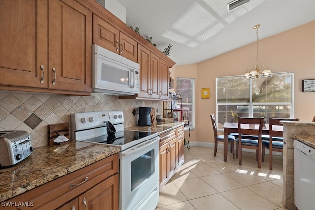 kitchen featuring pendant lighting, white appliances, an inviting chandelier, vaulted ceiling, and light tile patterned floors