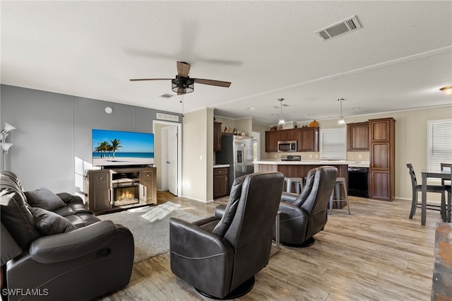 living room with ceiling fan, a textured ceiling, and light hardwood / wood-style flooring