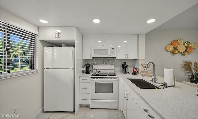 kitchen with white appliances, white cabinets, sink, tasteful backsplash, and light stone counters