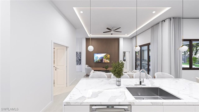 kitchen with ceiling fan, sink, light stone counters, pendant lighting, and white cabinets